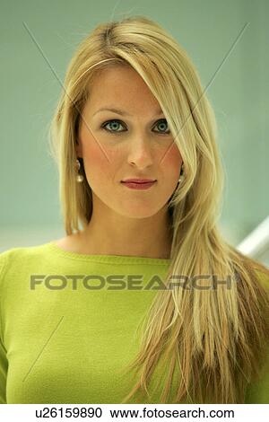 Stock Image - Portrait of young business woman with long blond hair wearing green sweater. Fotosearch