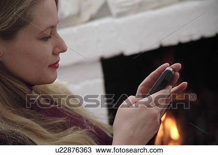 Woman using mobile phone by the fireplace, side view View Large Photo Image Stock Image - Woman using mobile phone by the fireplace, side view. Fotosearch