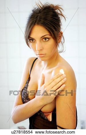 Young woman in bathroom, applying body lotion to her shoulder View Large Photo Image Picture - Young woman in bathroom, applying body lotion to her shoulder. Fotosearch