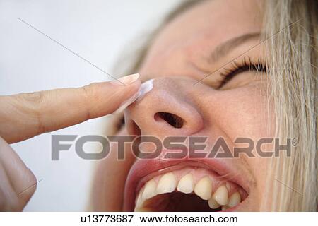 Stock Photo - Close up of woman's face with a spot of sunscreen on her nose, laughing. Fotosearch