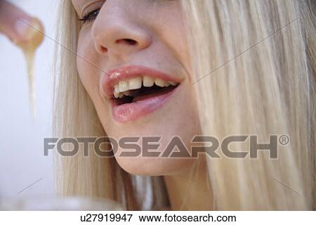 Young blond woman licking honey off her finger, side view, close up View Large Photo Image Stock Photo - Young blond woman licking honey off her finger, side view, close up. Fotosearch