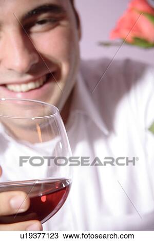 Stock Image - Young man drinking red wine, close up. Fotosearch