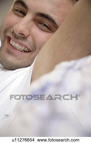 Young man stretching on bed, smiling View Large Photo Image Picture - Young man stretching on bed, smiling. Fotosearch