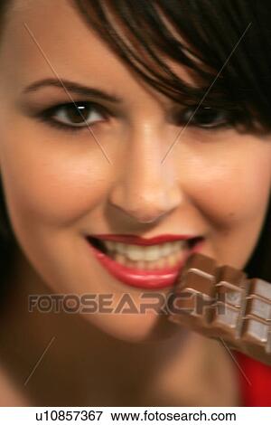 Stock Photo - Young woman eating bar of chocolate, portrait, close up. Fotosearch