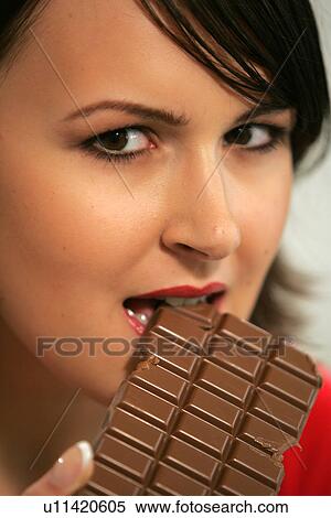 Stock Photography - Young woman eating bar of chocolate, portrait, close up. Fotosearch