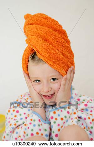 Stock Image - Girl wearing bathrobe and towel around hair, hands on cheeks. Fotosearch