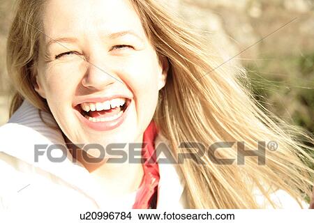 Portrait of blond woman smiling, blinded by the sunlight View Large Photo Image Picture - Portrait of blond woman smiling, blinded by the sunlight. Fotosearch