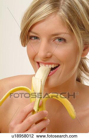 Stock Image - Portrait of Woman eating banana. Fotosearch