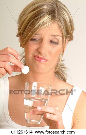 Woman dropping fizzy tablet into water, unhappy View Large Photo Image Picture - Woman dropping fizzy tablet into water, unhappy. Fotosearch