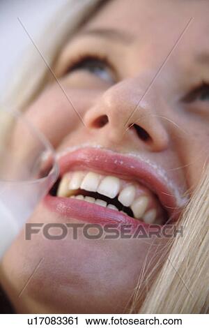 Stock Image - Young blond woman drinking milk from a glass, milksop, close up. Fotosearch
