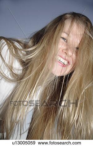 Stock Photo - Young blond woman in front of dark clouds, portrait. Fotosearch