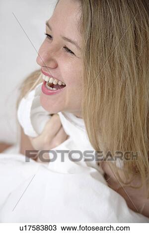 Young blond woman sitting up in bed, laughing View Large Photo Image Stock Image - Young blond woman sitting up in bed, laughing. Fotosearch