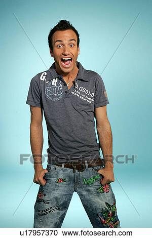 Stock Image - Young man in casual clothing, expressing happiness, studio shot. Fotosearch