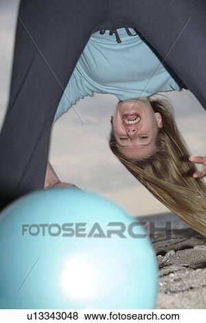 Young woman at the beach, tossing a ball through straddled legs View Large Photo Image Stock Photo - Young woman at the beach, tossing a ball through straddled legs. Fotosearch