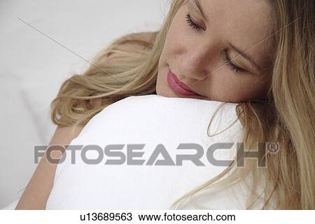 Young woman clutching pillow while sleeping View Large Photo Image Stock Image - Young woman clutching pillow while sleeping. Fotosearch