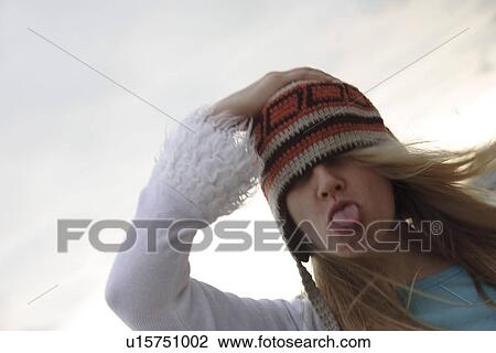 Stock Image - Young woman wearing knitted cap, running and laughing at the beach, close up. Fotosearch