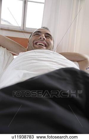 Young man lying in bed, relaxing View Large Photo Image Stock Image - Young man lying in bed, relaxing. Fotosearch