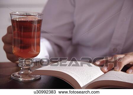 Young man reading a book with a mug of tea View Large Photo Image Stock Image - Young man reading a book with a mug of tea. Fotosearch