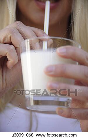 Stock Photo - Woman drinking milk with straw from glass, close up. Fotosearch