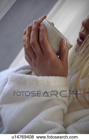 Stock Photo - Woman in bathrobe holding cup of tea. Fotosearch