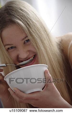 Young blond woman eating bowl of cereals, laughing, close up View Large Photo Image Stock Photo - Young blond woman eating bowl of cereals, laughing, close up. Fotosearch