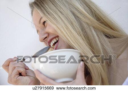 Young blond woman eating bowl of cereals, laughing, close up View Large Photo Image Stock Photo - Young blond woman eating bowl of cereals, laughing, close up. Fotosearch