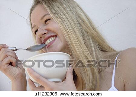 Young blond woman eating bowl of cereals, laughing, close up View Large Photo Image Stock Photograph - Young blond woman eating bowl of cereals, laughing, close up. Fotosearch