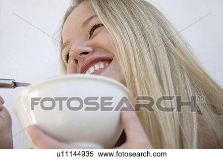 Young blond woman eating bowl of cereals, laughing, close up View Large Photo Image Stock Photography - Young blond woman eating bowl of cereals, laughing, close up. Fotosearch