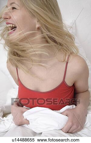 Young blond woman sitting up in bed, laughing View Large Photo Image Stock Photography - Young blond woman sitting up in bed, laughing. Fotosearch