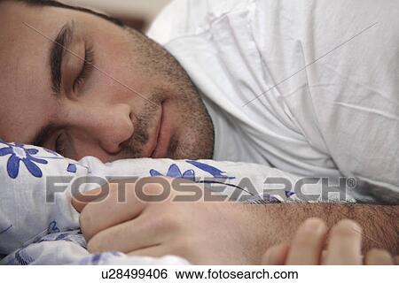 Young man clutching pillow while sleeping View Large Photo Image Stock Photograph - Young man clutching pillow while sleeping. Fotosearch