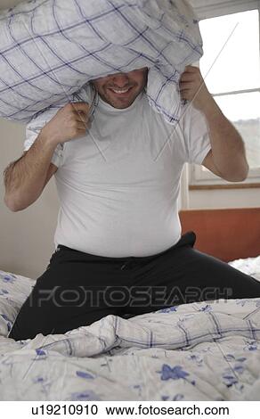 Young man in a pillow fight View Large Photo Image Stock Image - Young man in a pillow fight. Fotosearch
