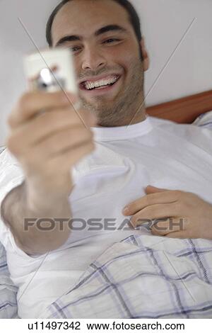 Young man in bed taking picture of himself with camera mobile View Large Photo Image Stock Image - Young man in bed taking picture of himself with camera mobile. Fotosearch