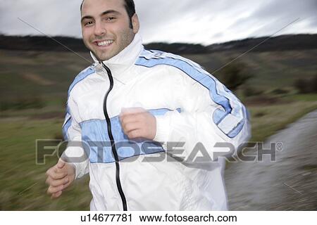 Stock Image - Young man jogging in spite of bad weather. Fotosearch