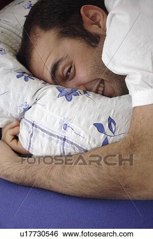 Young man lying in bed, head resting on the pillow View Large Photo Image Stock Photograph - Young man lying in bed, head resting on the pillow. Fotosearch