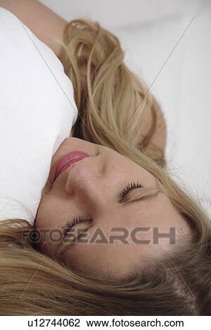 Young woman clutching pillow while sleeping View Large Photo Image Stock Image - Young woman clutching pillow while sleeping. Fotosearch