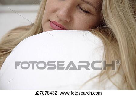 Young woman clutching pillow while sleeping View Large Photo Image Stock Image - Young woman clutching pillow while sleeping. Fotosearch