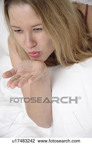 Young woman lying in bed, blowing someone a kiss View Large Photo Image Stock Image - Young woman lying in bed, blowing someone a kiss. Fotosearch