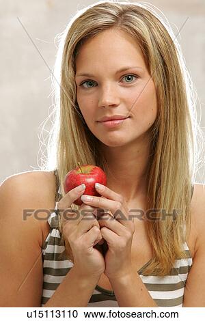 Young woman with long blond hair eating an apple, portrait View Large Photo Image Stock Image - Young woman with long blond hair eating an apple, portrait. Fotosearch