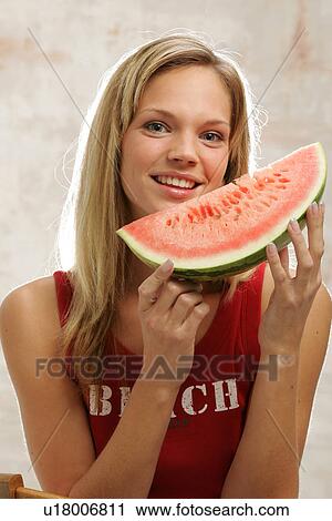 Young woman with long blond hair eating a slice of watermelon, portrait View Large Photo Image Stock Image - Young woman with long blond hair eating a slice of watermelon, portrait. Fotosearch