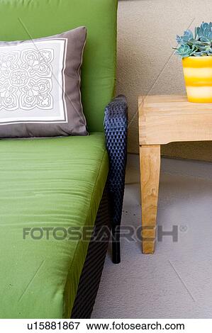 Stock Photo - Detail of plant on table next to green chair. Fotosearch