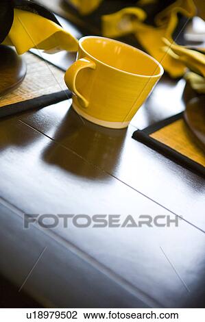 Stock Image - Detail of yellow cup surrounded by yellow place settings. Fotosearch