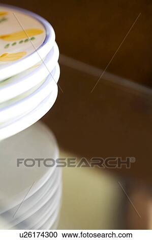 Stock Image - Four plates stacked on a glass table. Fotosearch