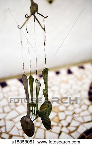 Stock Image - Silverware wind chime hanging over tile mosaic. Fotosearch