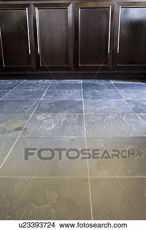 Picture - Detail of slate tile floor and wood cabinets.. Fotosearch