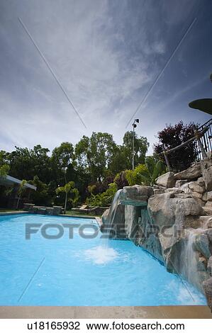 Stock Image - Swimming pool with rock waterfall. Fotosearch