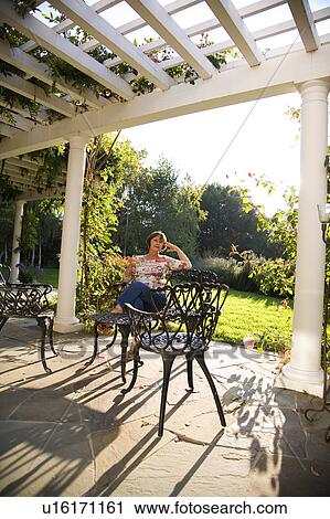 Stock Image - Woman in outdoor patio chair. Fotosearch