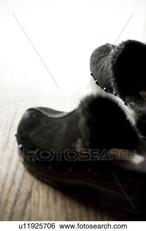 Stock Photograph - Detail of black slippers on hardwood floor. Fotosearch