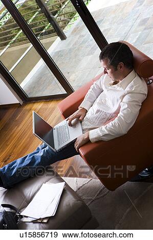 Man working on laptop in modern living room View Large Photo Image Stock Photo - Man working on laptop in modern living room. Fotosearch