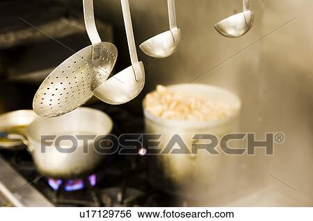 Stock Photograph - Serving Spoons Hanging over Stovetop. Fotosearch
