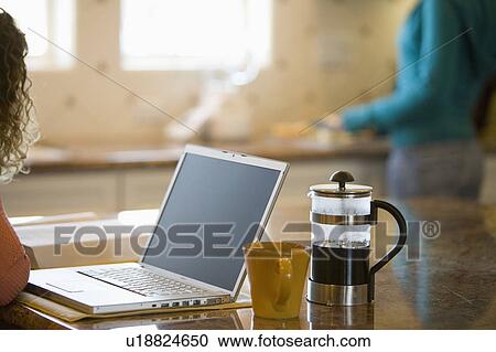Young woman drinking coffee and working on her laptop in the morning View Large Photo Image Stock Image - Young woman drinking coffee and working on her laptop in the morning. Fotosearch